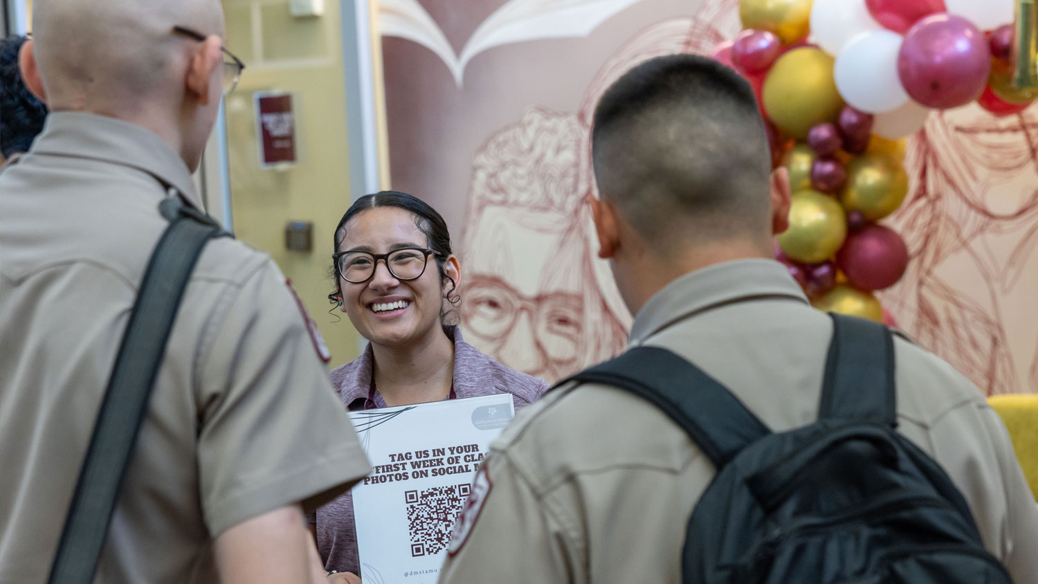DMS staff member engaging with two Corps of Cadets students at an event.